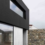 Z dvora vede dveřní otvor do chodby, která prochází celým domem a vrcholí v obývacím pokoji, kde se negativní tvar kamenného štítu opakuje ve třech pevných skleněných panelech. Foto: Gilbert McCarragher Z dvora vede dveřní otvor do chodby, která prochází celým domem a vrcholí v obývacím pokoji, kde se negativní tvar kamenného štítu opakuje ve třech pevných skleněných panelech. Foto: Gilbert McCarragher