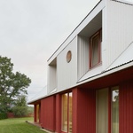 Interakce městské a venkovské scenérie jsou impulsem pro zářivě červený dům s třpytivou trojúhelníkovou střechou, s terasami a otvory, které zprostředkovávají aktivní pobyt obyvatelů vně domu. Foto: Madara Kuplā