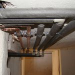 Detail vedení potrubí pod stropem ve sklepě - V domě jsou trubky nově vedeny ve stěnách, výjimkou je pouze sklep, kde je veškeré vedení potrubí umístěno těsně pod stropem.