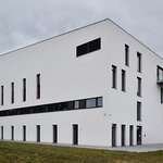 ZUŠ Karla Malicha v pohledu ze severu. Na delší stěně v přízemí jsou okna učeben, nad nimi nízká okna výtvarné učebny, v nejvyšší podlaží okna velkého sálu a nasávací otvory pro větrání budovy
