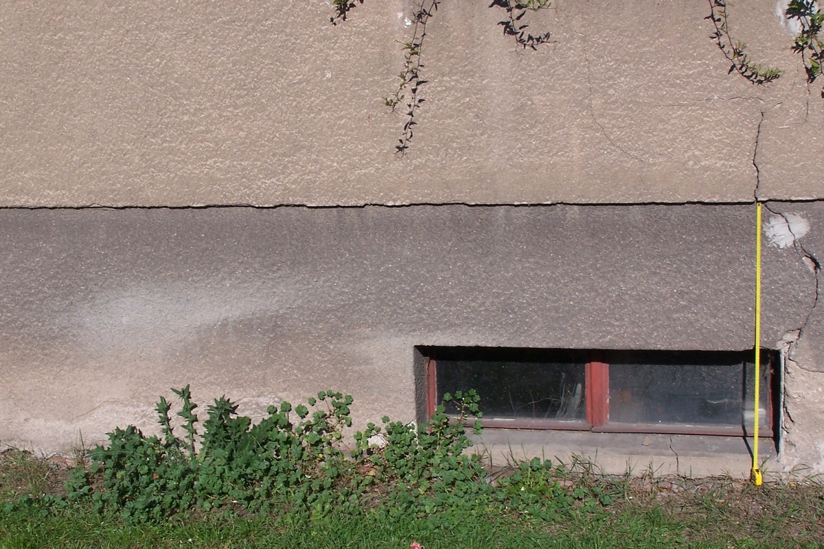 Omítka na soklu opadaná v důsledku vzlínání vlhkosti. Hydroizolace již neplní svůj účel, bude nutné ji vyměnit. Vpravo viditelná statická trhlina. Omítka na soklu opadaná v důsledku vzlínání vlhkosti. Hydroizolace již neplní svůj účel, bude nutné ji vyměnit. Vpravo viditelná statická trhlina.