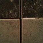 Kombinace příliš tlusté svislé a příliš tenké vodorovné spáry. Vodorovná spára nenavazuje vůbec, materiál zašpiněný, spára vyplněná lepidlem.