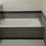 Na stěny byla použita bílá spárovačka, na dlažbu šedá. Odpad pod vanou je přístupný díky odnímatelné obkladačce na magnetech. I spára této obkladačky bude vytmelena. V případě nutnosti přístupu k odpadu bude muset být tmel obnoven.