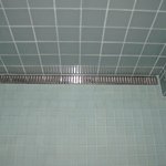 Detail odtokového žlabu - Sprchový kout je bezbariérový s mírným spádem ke kratší stěně, kde je umístěn odtokový žlab.