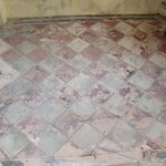 Vzhled původní betonové dlažby na verandě - Na verandě byla původní betonová dlažba natolik poškozená, že ji nebylo možné vyčistit ani zachránit; musela tedy být kompletně vybourána a na její místo bude repasována tatáž dlažba vybouraná z jiných prostor domu.