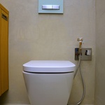 WC se závěsným systémem a tlačítkem Geberit doplňuje bidetová sprška korespondující svým tvarem s ostatními bateriemi v koupelně. Tlačítko barevně navazuje na skleněné tvárnice ve sprchovém koutě