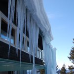 12 - Namrzání kondenzátu spojené s postupným sesuvem mas sněhu a ledu ze střechy. V dolní části snímku patrný přesah kryjící prostor pro pěší. © Petr Bohuslávek