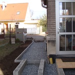 Plocha od brány ke garáži, kde byly původně položeny jen dva pásy betonových dlaždic, bude plně vydlážděná pojezdovými betonovými tvarovkami od firmy Best; stejnými tvarovkami, avšak pouze s pochozí nosností budou vydlážděny i ostatní plochy kolem domu, včetně chodníku od branky směrem k verandě.