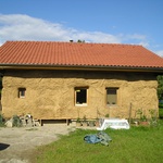 Rodinný dům „slamák“ ve výstavbě: z vnější strany po první vrstvě základních hliněných omítek, uvnitř hliněné omítky dokončeny.