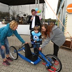 Osmiletý Michal Novotný nasedá na darovaný handbike od Lindabu za asistence své maminky (vpravo), marketingové manažerky Lindabu Petry Ždánské (vlevo) a moderátora akce – herce a režiséra Ondřeje Sokola.
