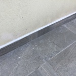 Dokončený detail soklu s nalepeným obkladem a spárou opatřenou trvale pružným tmelem
