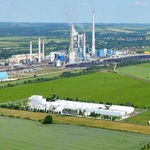 V popředí výrobní závod, v pozadí tepelná elektrárna Mělník. Vlevo uprostřed je vidět pásový dopravník na sádrovec. Zdroj: Rigips