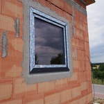 Pohled na osazené okno z exteriéru – páska je již přilepena na zdivo. Povrch stěrkové hmoty by měl být zarovnán, pro přesnější osazení zateplovacího systému.