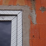 Detail – osazené okno z exteriéru. Na tento povrch přijde zateplovací systém, bude přetažený přes rám okna.  Povrch stěrkové hmoty by měl být zarovnán, pro přesnější osazení zateplovacího systému.