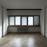 Hlavní obytná místnost v jednom z typických bytů o dispozici 1+1, zde s původní parketovou podlahou.