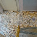Na dlažbě bylo na vrstvě vyrovnávací stěrky nalepeno linoleum; po jeho odstranění vypadala dlažba velmi neutěšeně.